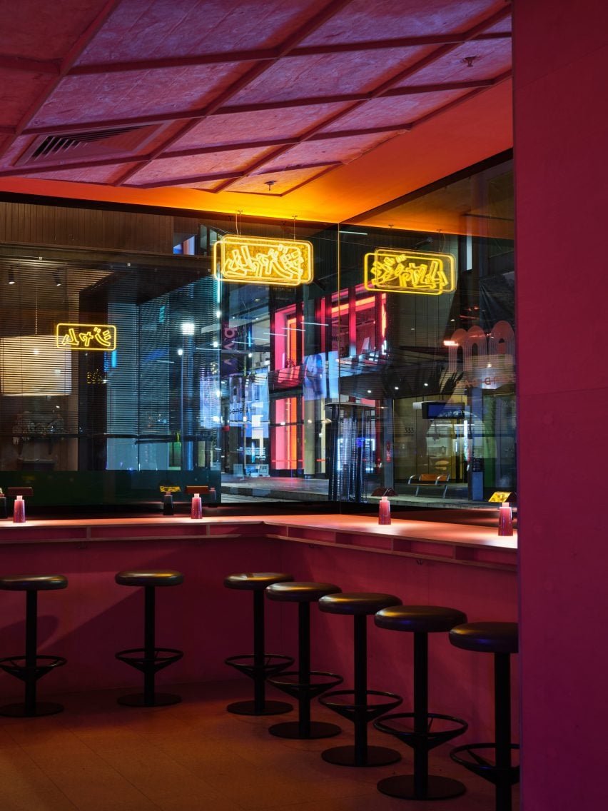 Benches in front of a window in a pink-toned bar